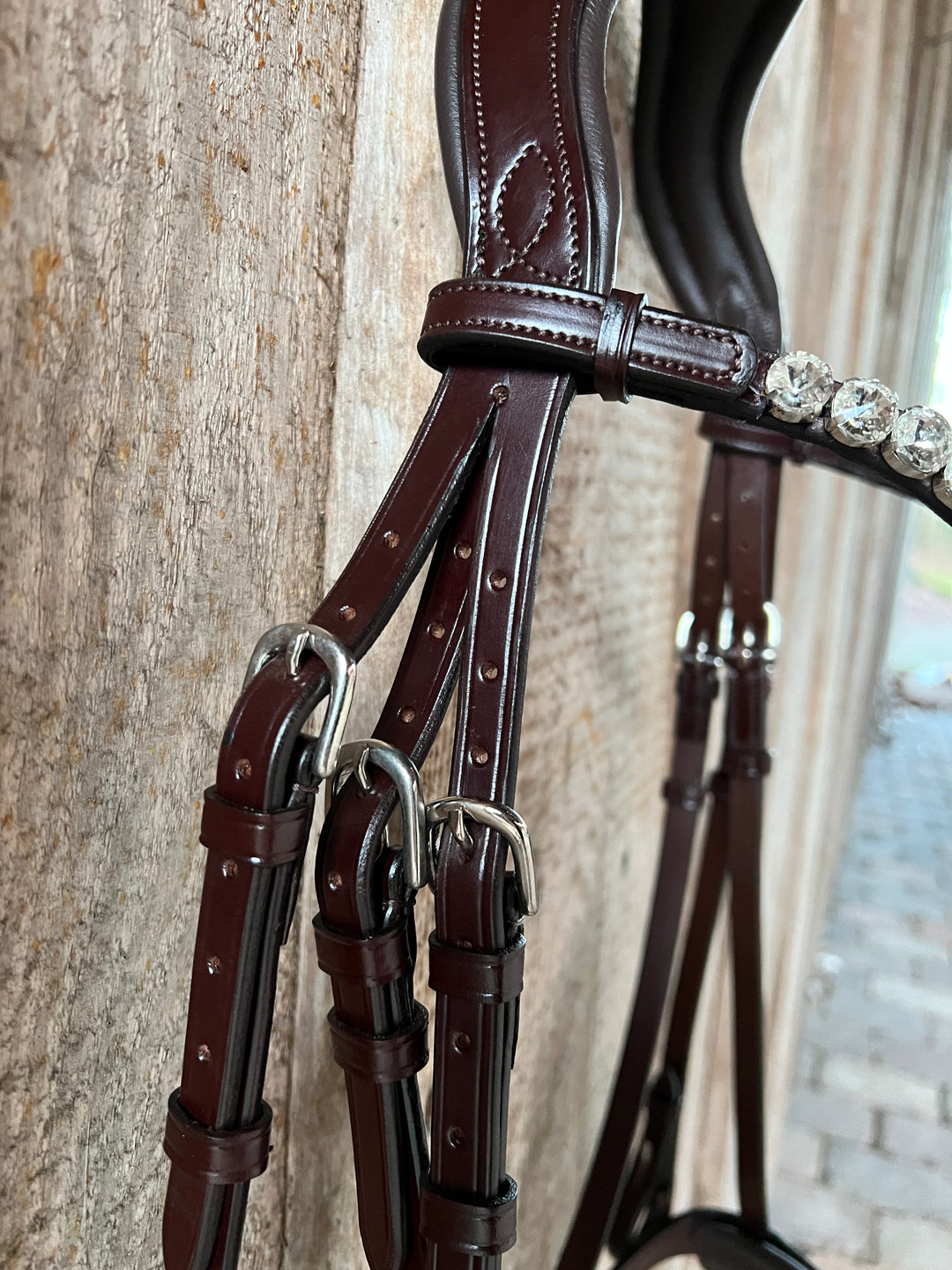 Anatomisches Genickstück mit einem Stirnriemen der verziert ist mit brillanten großen Rivoli Steinen und Quick-Change-Verschluss. Italienisches Qualitätsleder in Rotbraun mit klassischen runden Schnallen.